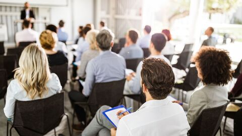 Erwachsene Menschen sitzen in einer Veranstaltung.