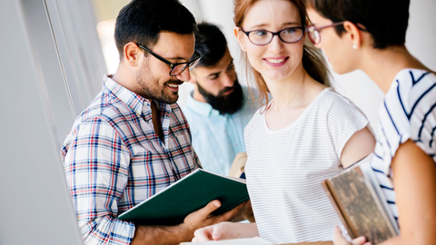Junge Menschen stehen zusammen und unterhalten sich. 