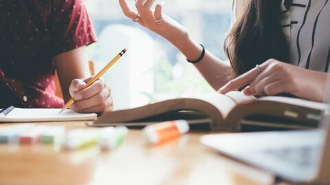 Eine Schülerin und ein Schüler lernen gemeinsam. Vor ihnen liegen aufgeschlagene Bücher.
