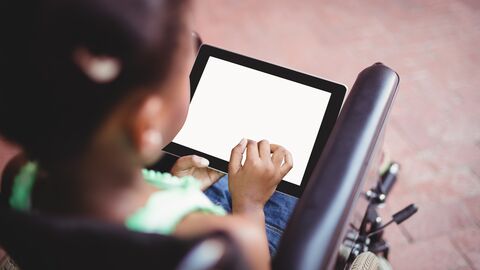 Ein Mädchen, das in einem Rollstuhl sitzt, kommuniziert mit einem Tablet.