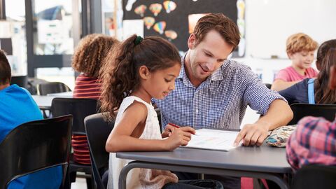 Lehrer hilft einer Schülerin im Unterricht