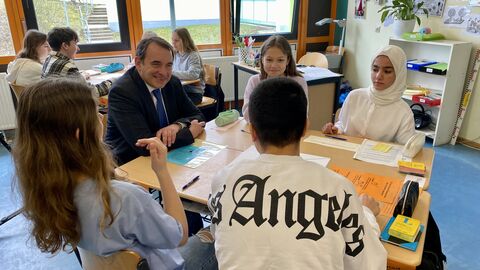 Kultusminister Lorz sitzt am Tisch mit einer Gruppe Schülerinnen und Schüler, ins Gespräch vertieft. 