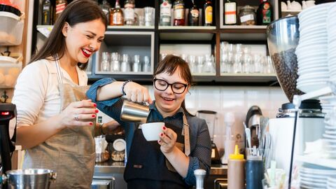 Junge Frau mit Downsyndrom bereitet Kaffee zu
