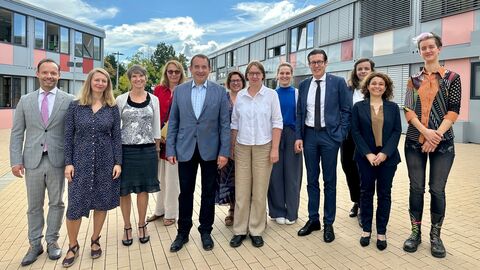 Kultusminister Lorz mit einer Gruppe Personen vor einem Gebäude. Alle stehen nebeneinander und lächeln.