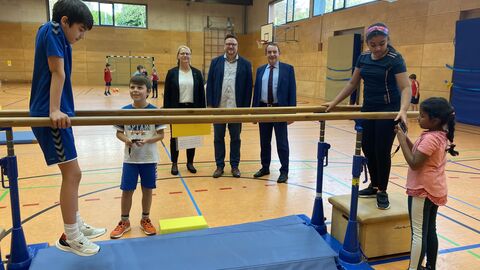Kultusminister Prof. Dr. R. Alexander Lorz und Lehrkräfte und Schülerinnen und Schüler der Grundschule am Eichwäldchen in Oberursel. Ein Junge stützt sich auf einen Barren.