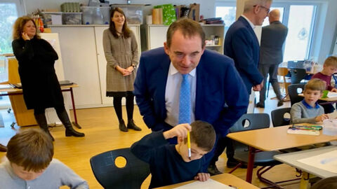Kultusminister Lorz schaut Kindern beim Male über die Schulter, im Hintergrund sind weitere Lehrerinnen. 
