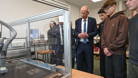 Armin Schwarz und Schüler begutachten einen Glaskasten.