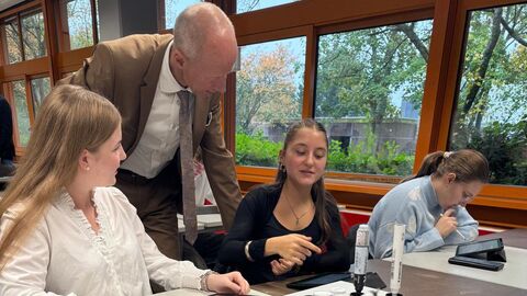 Bildungsminister spricht mit Schülerinnen in einem Klassenzimmer.