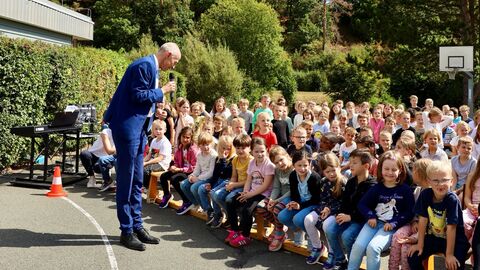 Kultusminister Armin Schwarz besucht am Aktionstag der Feuerwehr die Wigand-Gerstenberg-Schule in Frankenberg. Viele Schülerinnen und Schüler sitzen draußen auf den Bänken und hören ihm zu.
