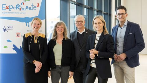 Fünf Personen stehen nebeneinander - hinter ihnen ein Plakat mit der Aufschrift "Experimente hoch 3"