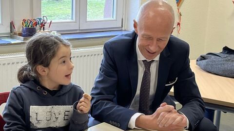 Bildungsminister Schwarz und ein Kind sitzen an einem Tisch.