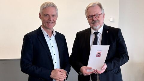 Staatssekretär Dr. Manuel Lösel steht neben Norbert Kissel, der eine Urkunde in Händen hält.