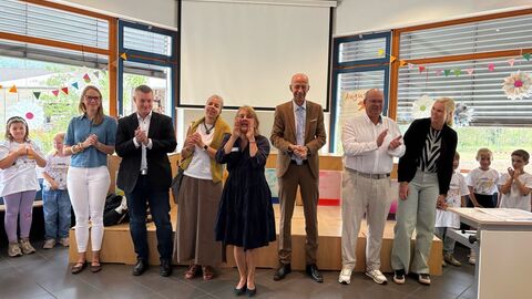 Bildungsminister Schwarz steht mit mehreren Menschen nebeneinander in einem Klassenraum.