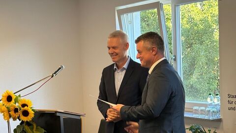 Staatssekretär Lösel und Ingo Stechmann stehen nebeneinander und reichen sich die Hand.