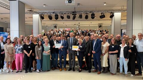 Über 50 Personen stehen in einer Halle zusammen.