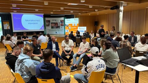 Bildungsminister Schwarz sitzt mit Schülerinnen und Schülern in einem Stuhlkreis